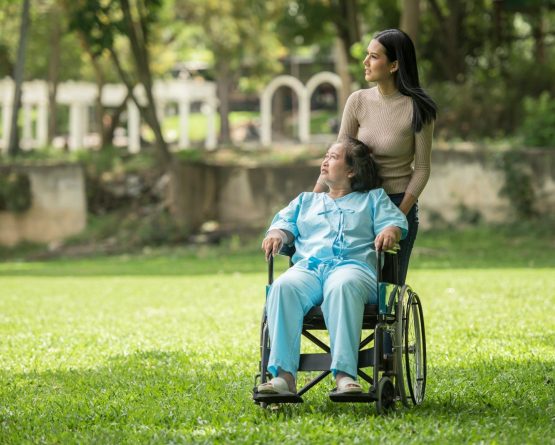 A woman in a wheelchair standing next to a man in a park